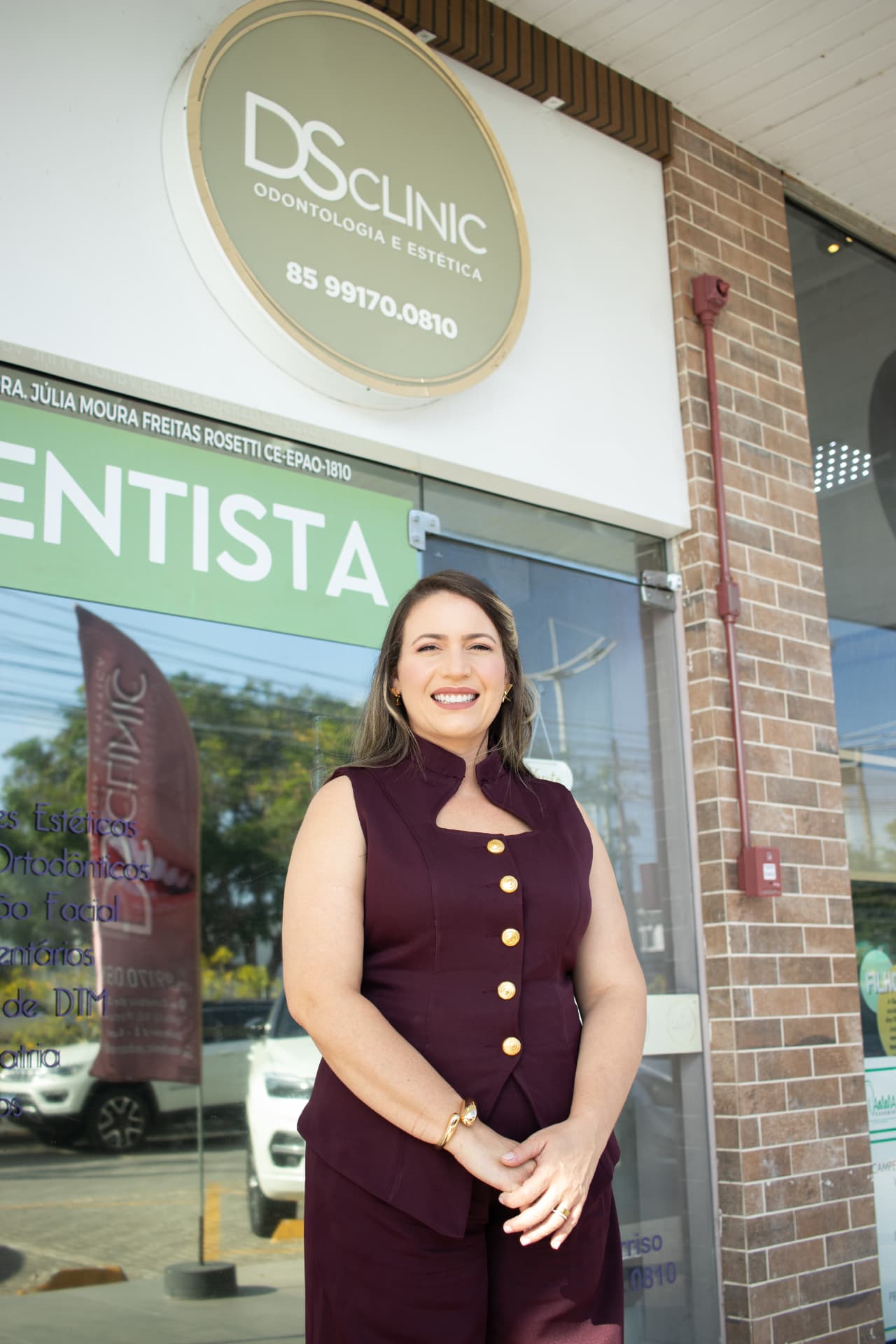 Dra. Júlia Moura Freitas Rosetti na fachada da DS Clinic, clínica de dentista em Eusébio